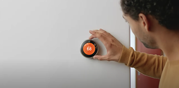 Homeowner adjusting their smart thermostat enrolled in the Peak Time Savings program